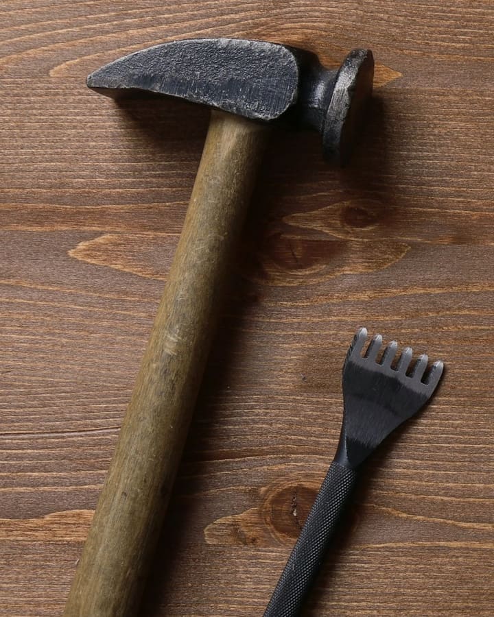 Hammer og lærverktøy på et trebord.